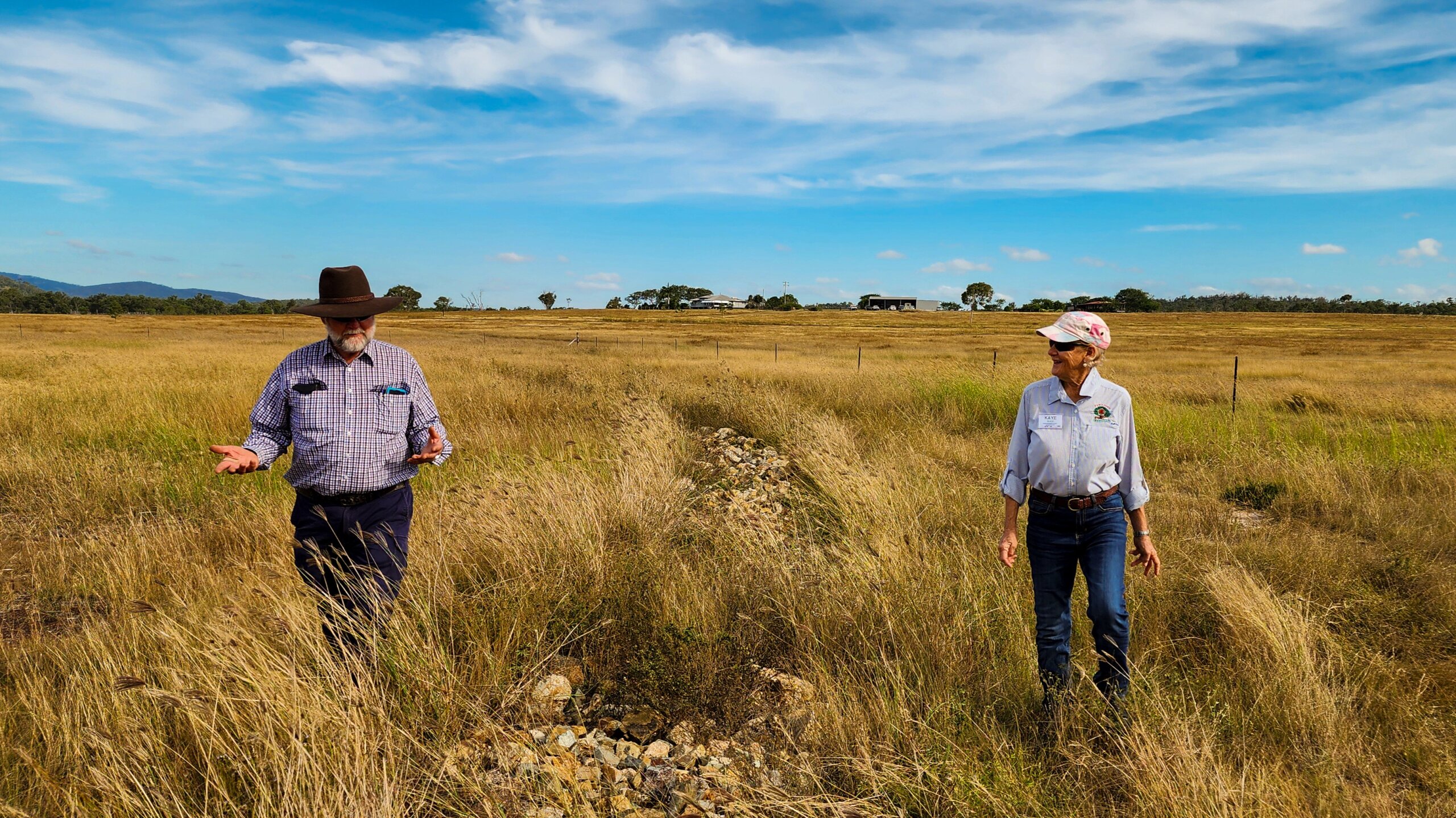 A man and a woman walking through high grass talking