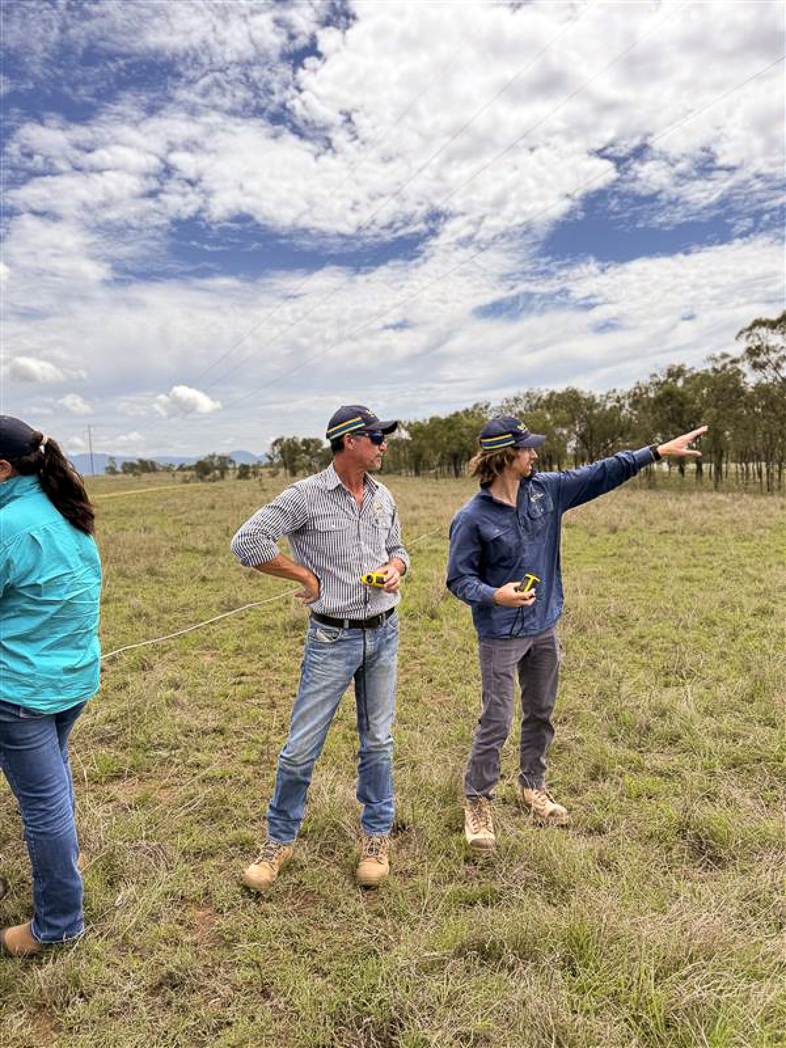 Two men standing in a field with one pointing towards the horizon