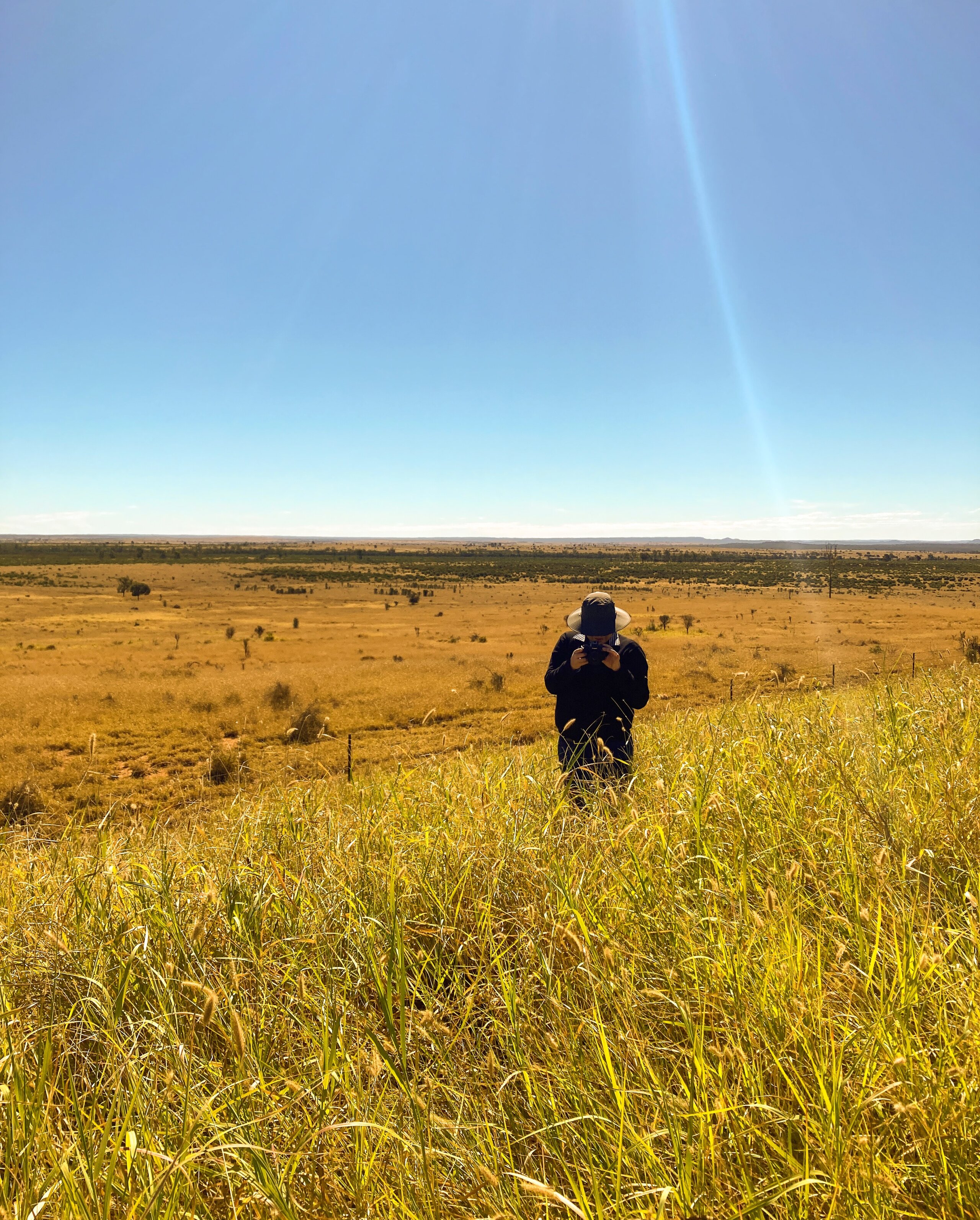 A man standing in a field taking a photo