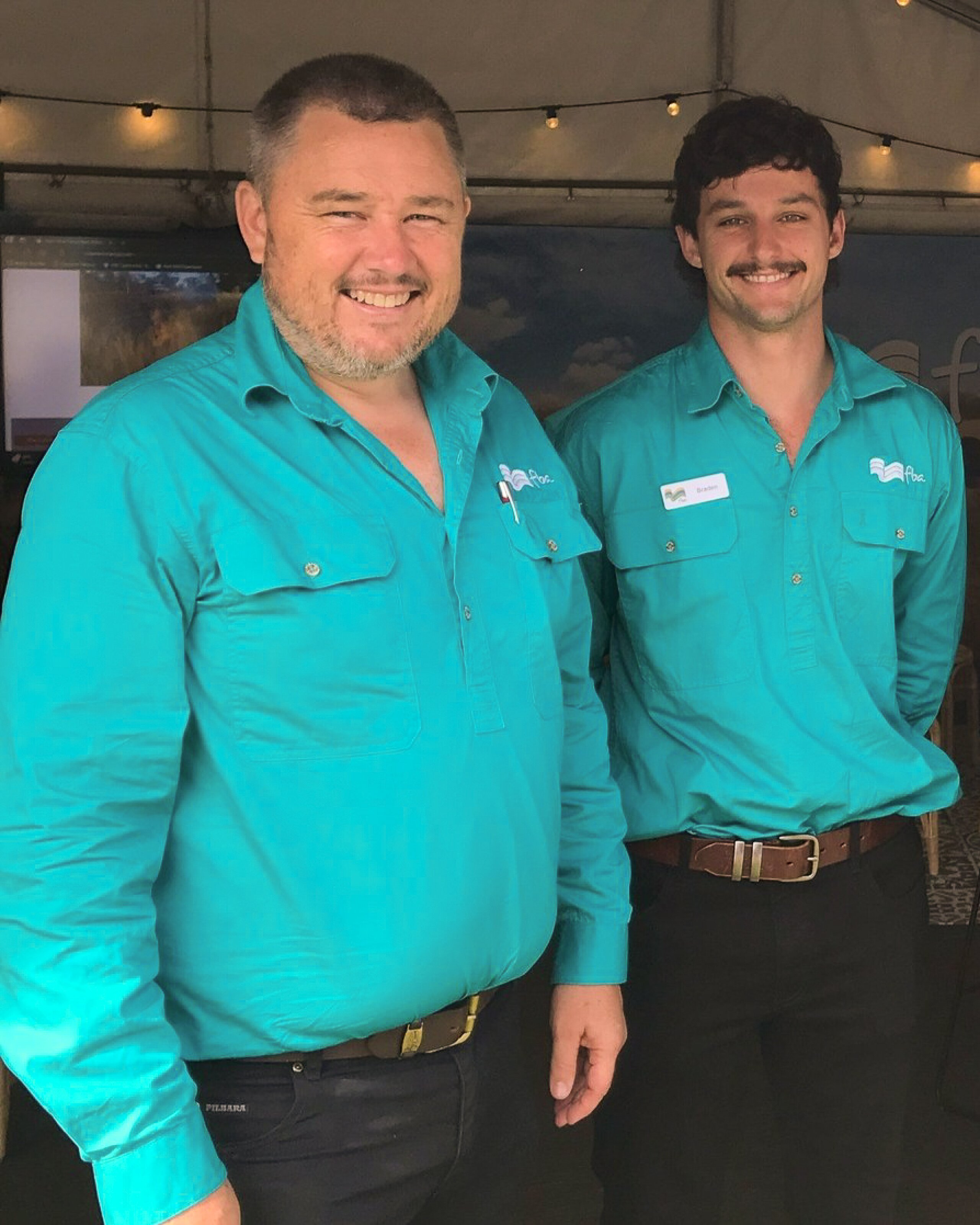 Two men standing and smiling at the camera