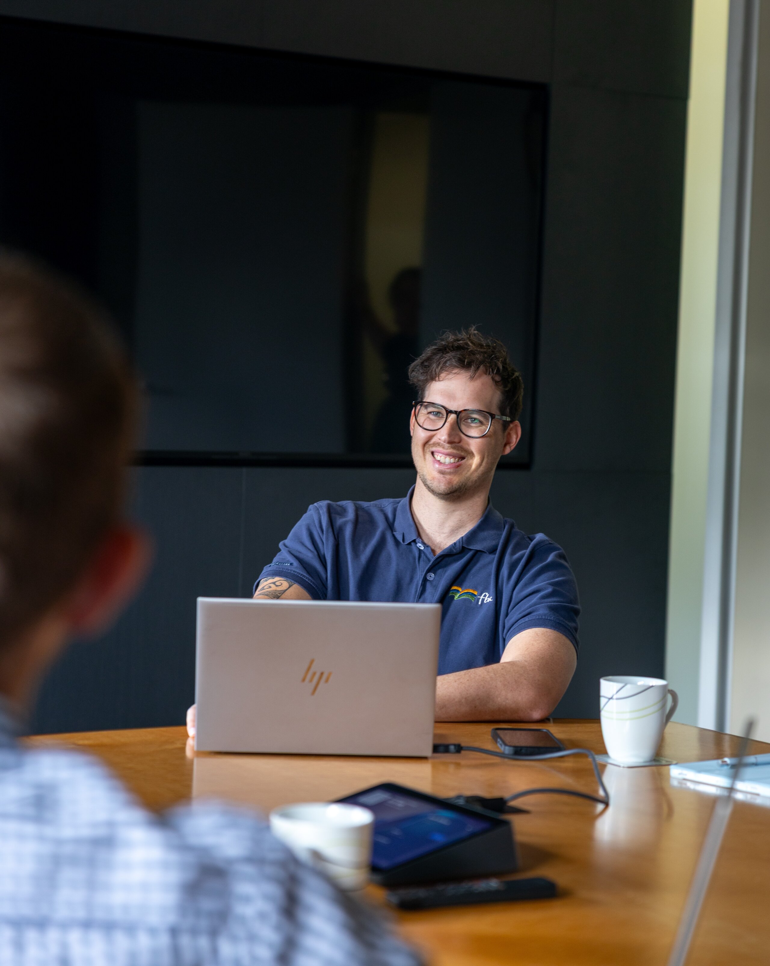 A man sitting at a table with his laptop smiling