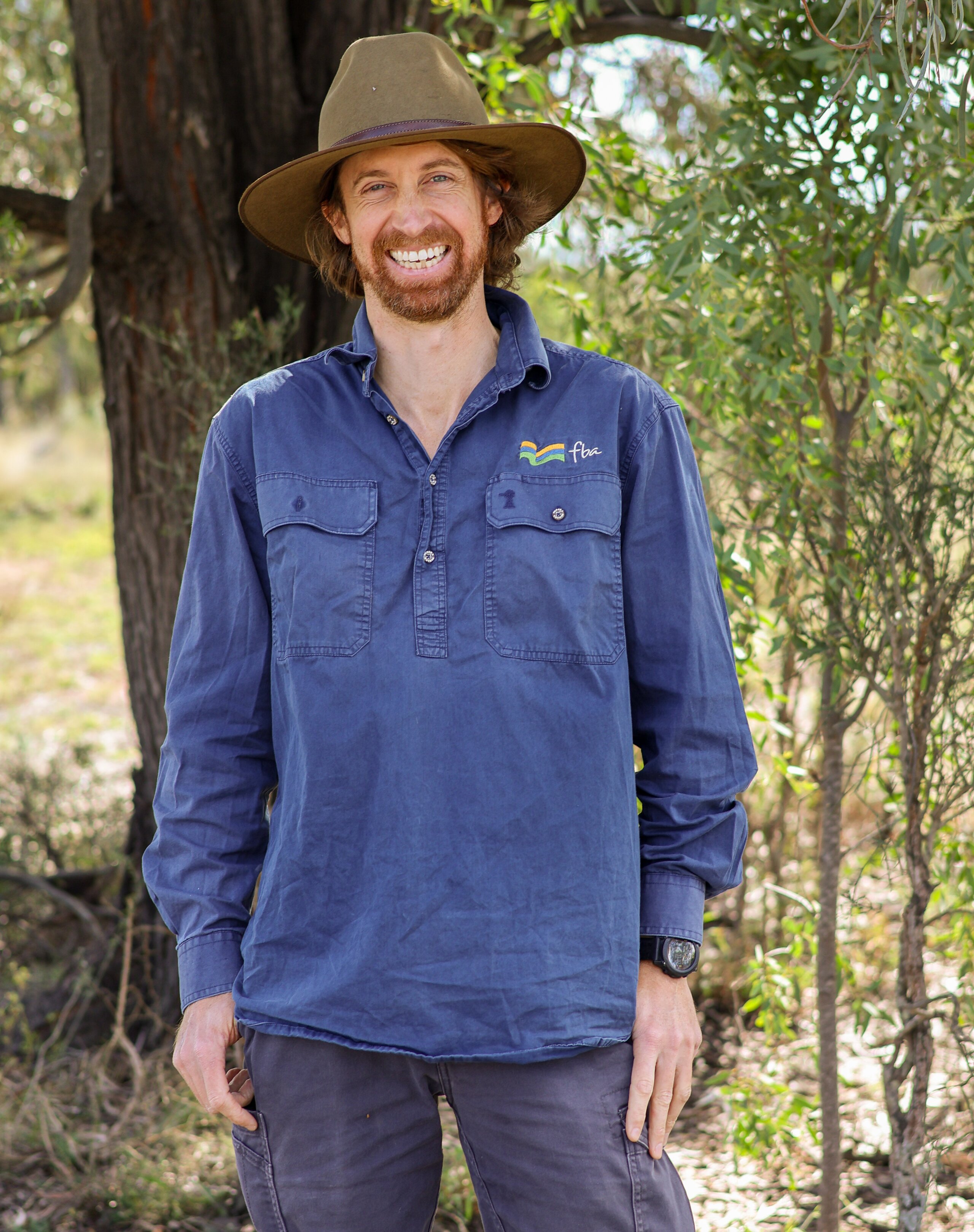 A man standing in front of a tree smiling at the camera