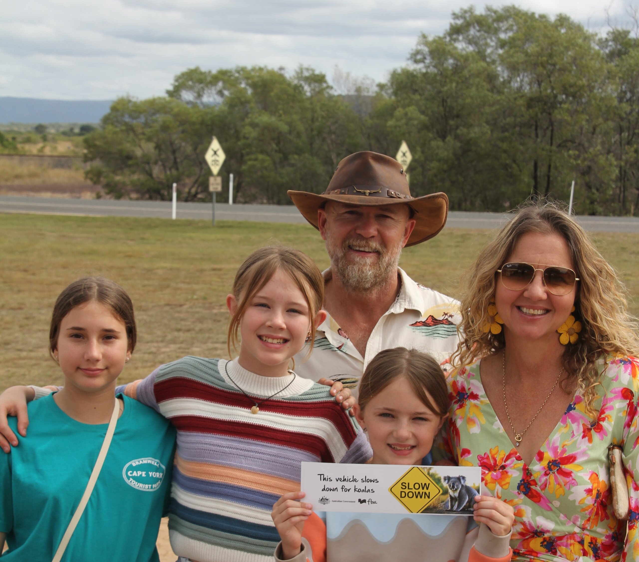 Family holding a slow down for koalas bumper sticker