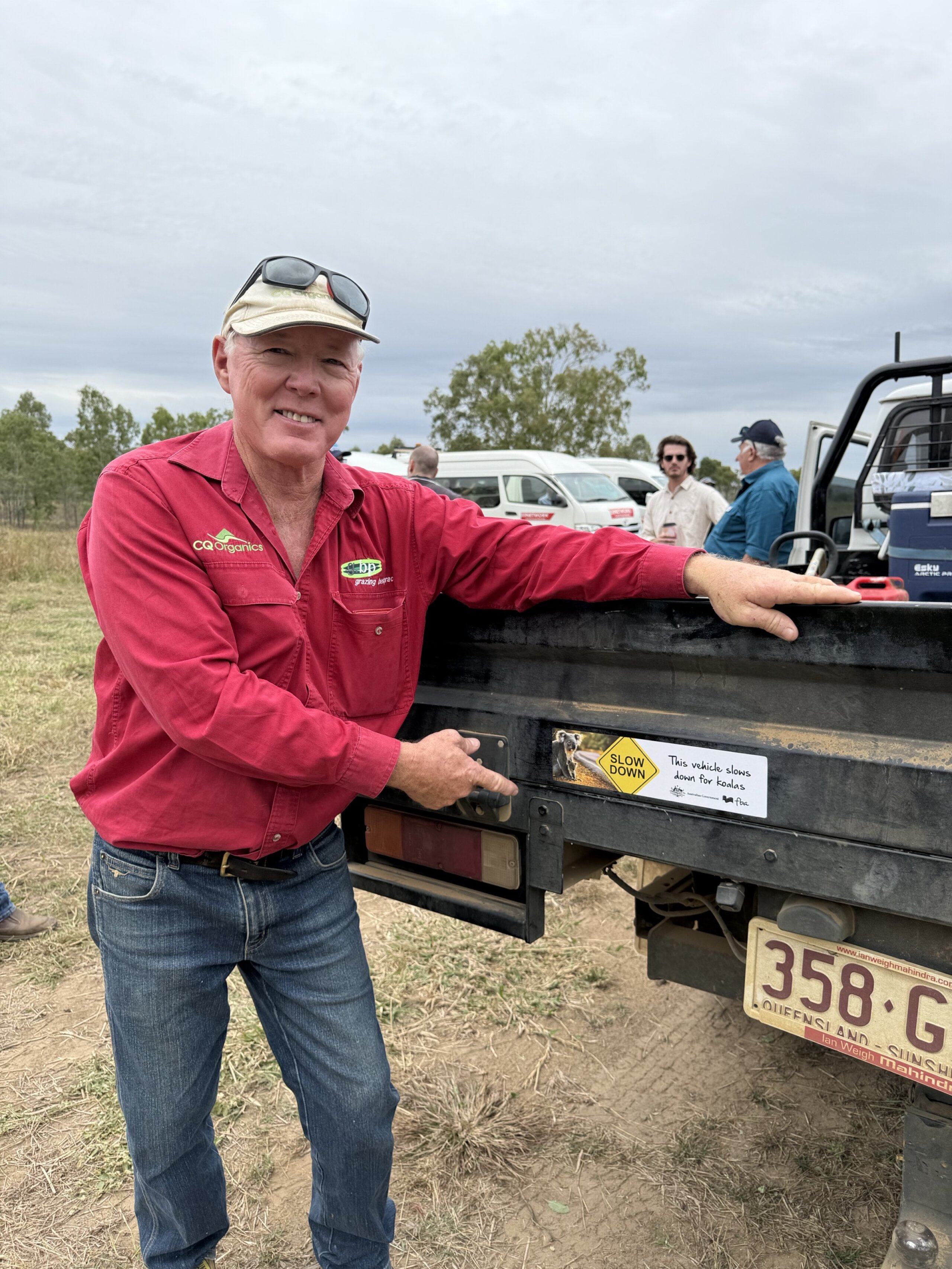 a CQ landmanager pointing to his car with a slow down for koalas bumper sticker displayed on it
