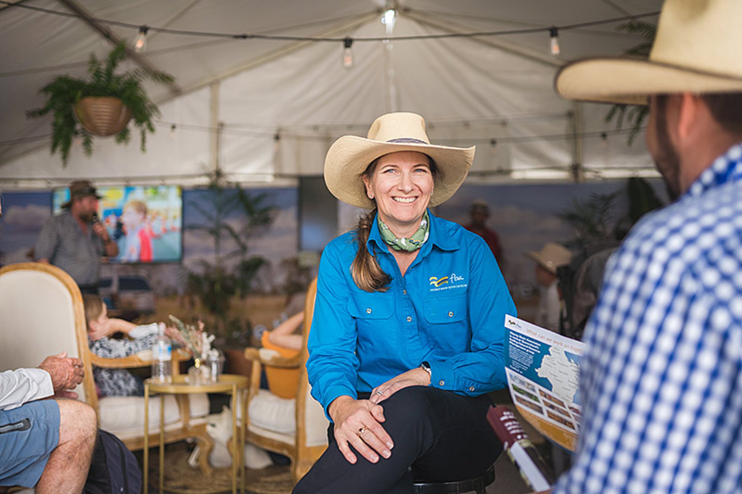 FBA staff member sits in an event space talking to a member of the public.