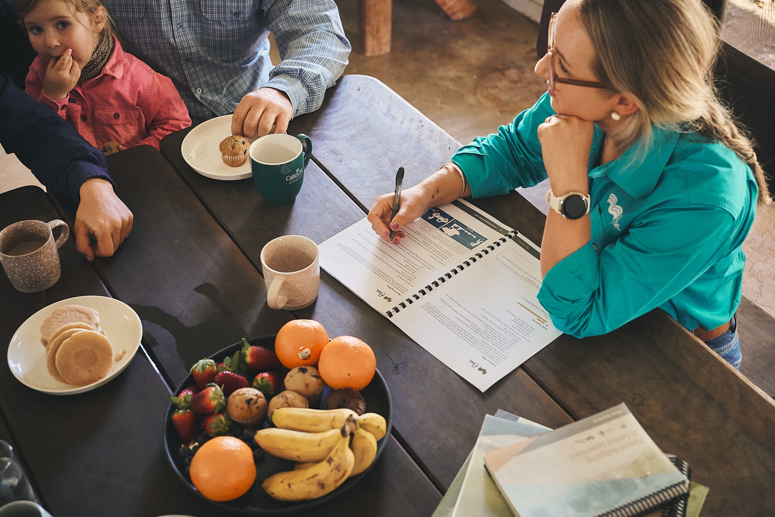 An FBA staff member discusses information from a document at a table with a farming family