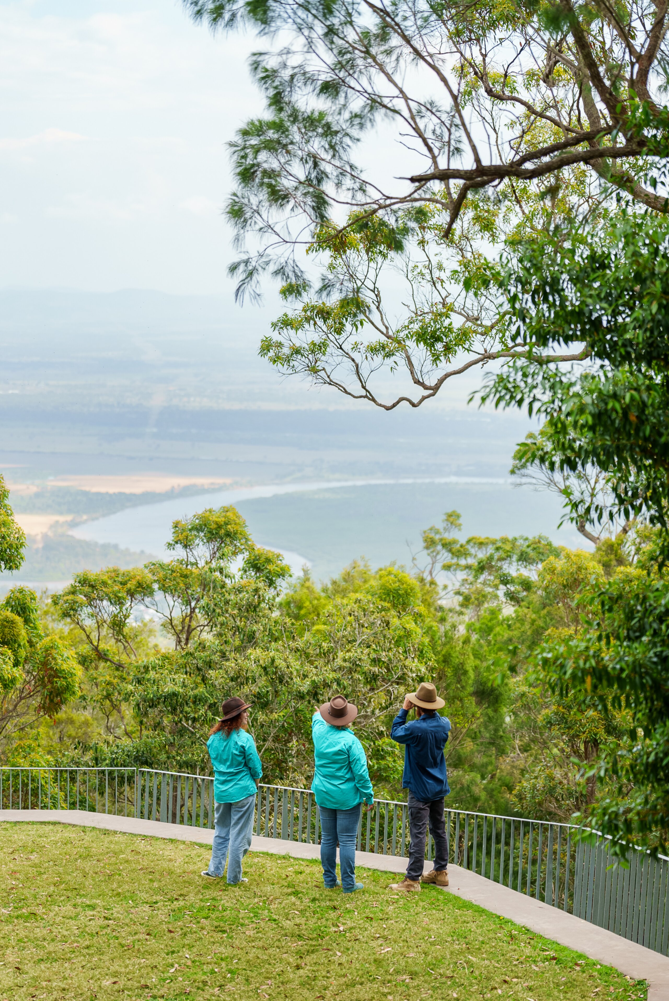 Three FBA staff stand looking at the landscape from Mt Archer.
